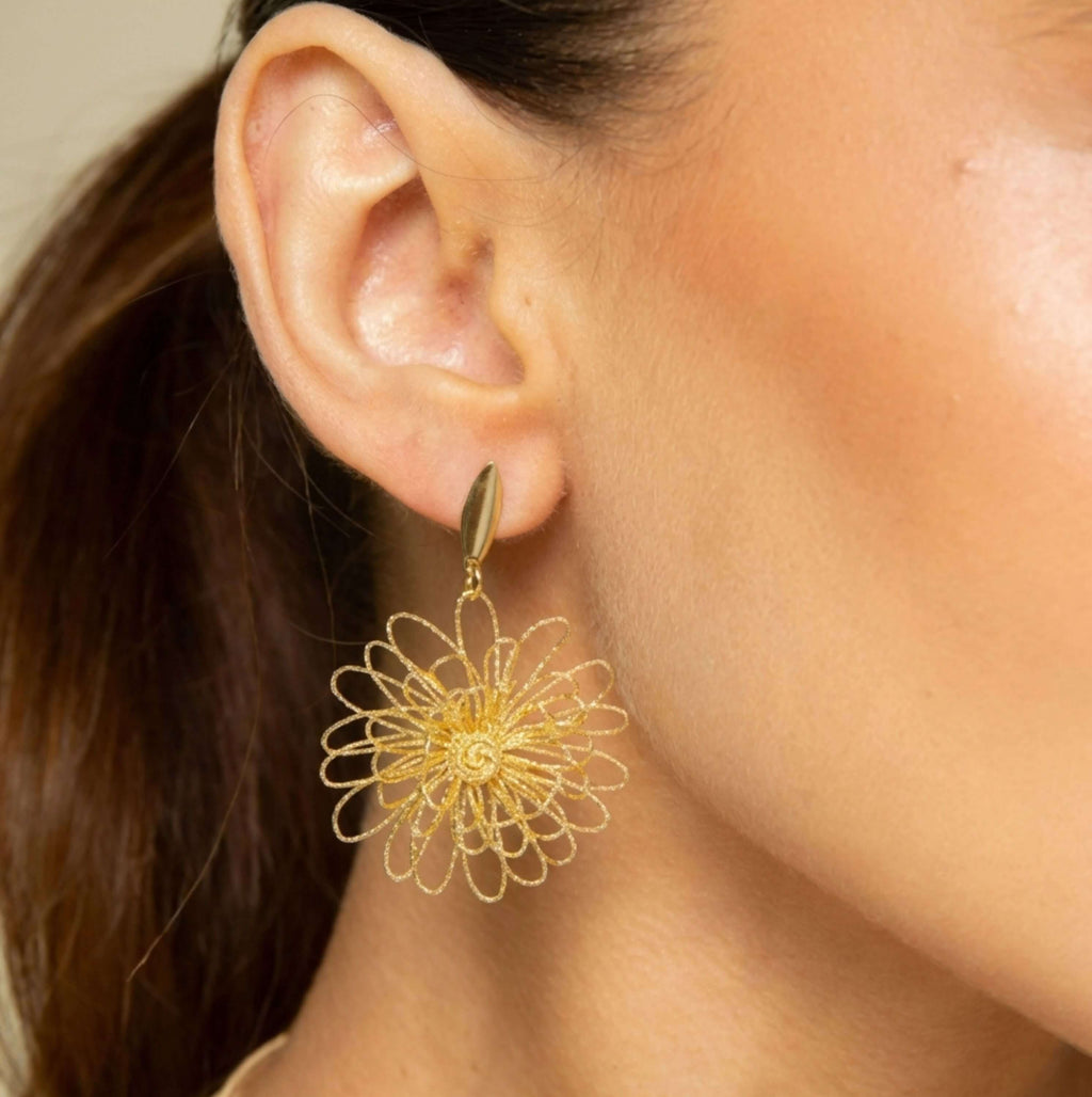 gold dangle earring with a flower-like openwork design.