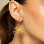 gold dangle earring with a flower-like openwork design.
